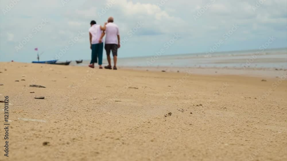 Asian senior couple walking happily by the beach. Well plan retired lifestyle no financial problem Asian senior couple walking happily by the beach. Well plan retired lifestyle no financial problem