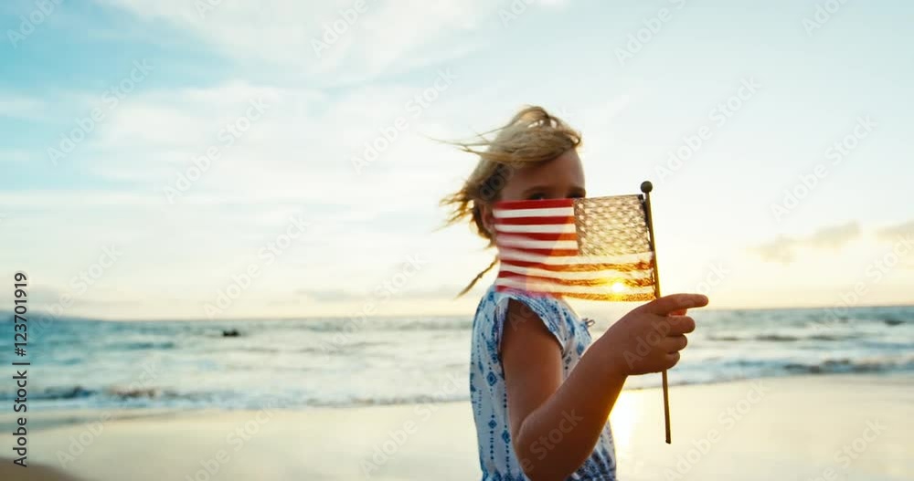 Cute young girl with American Flag on beach at sunset