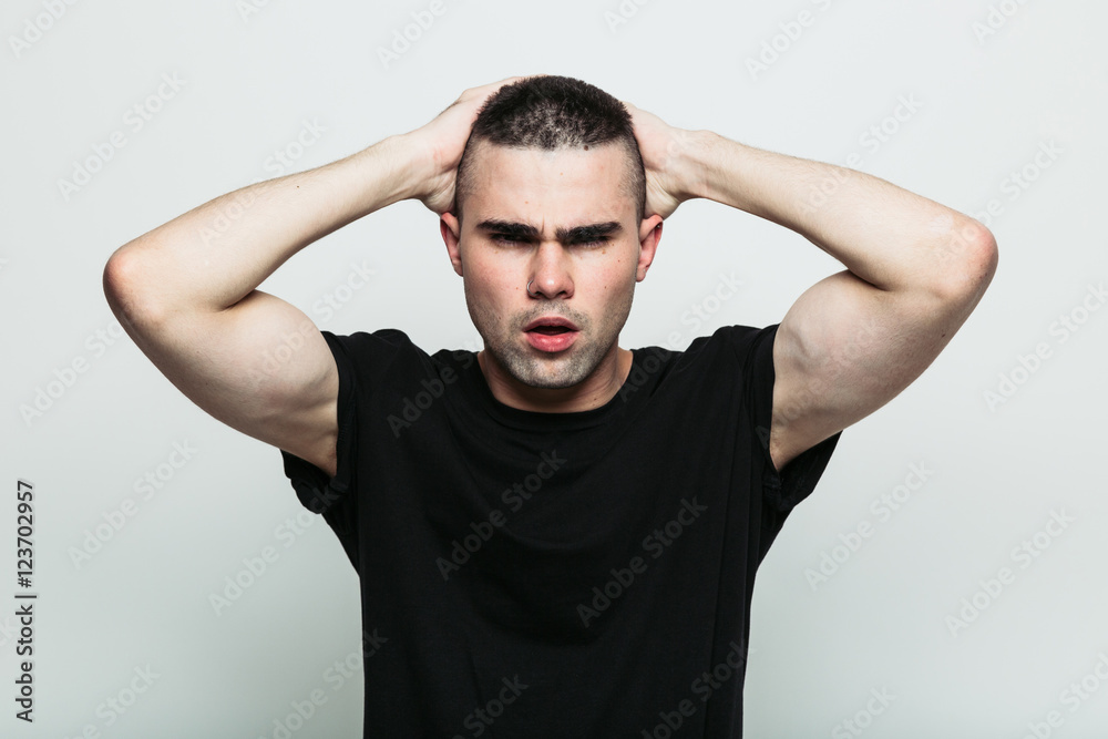 Front view of angry model man posing in studio with hands on head. Isolate. Front view of angry model man posing in studio with hands on head. Isolate.