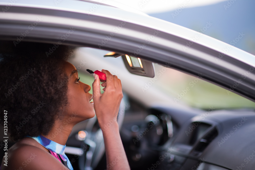 Naklejka premium a young African-American woman makeup in the car