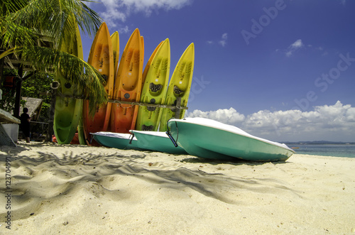 colorful stacking kayaks on white sandy beach at sunny day. blue sky and clear sea water background.image taken at Kapas Island (Cotton Island), Malaysia photo