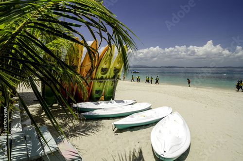 colorful stacking kayaks on white sandy beach at sunny day. blue sky and clear sea water background.image taken at Kapas Island (Cotton Island), Malaysia photo