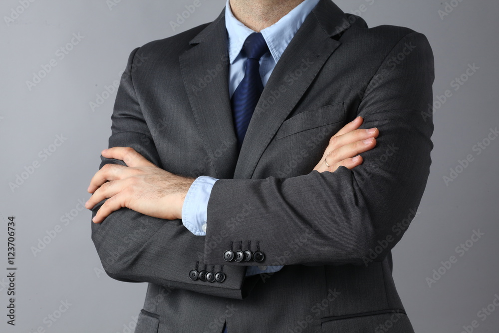 Businessman standing with arms crossed isolated in gray bakground Businessman standing with arms crossed isolated in gray bakground