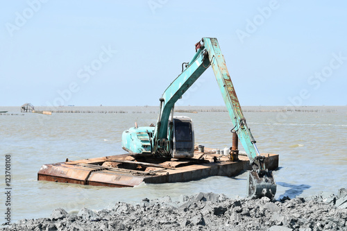 heavy organge excavator with standing on sea