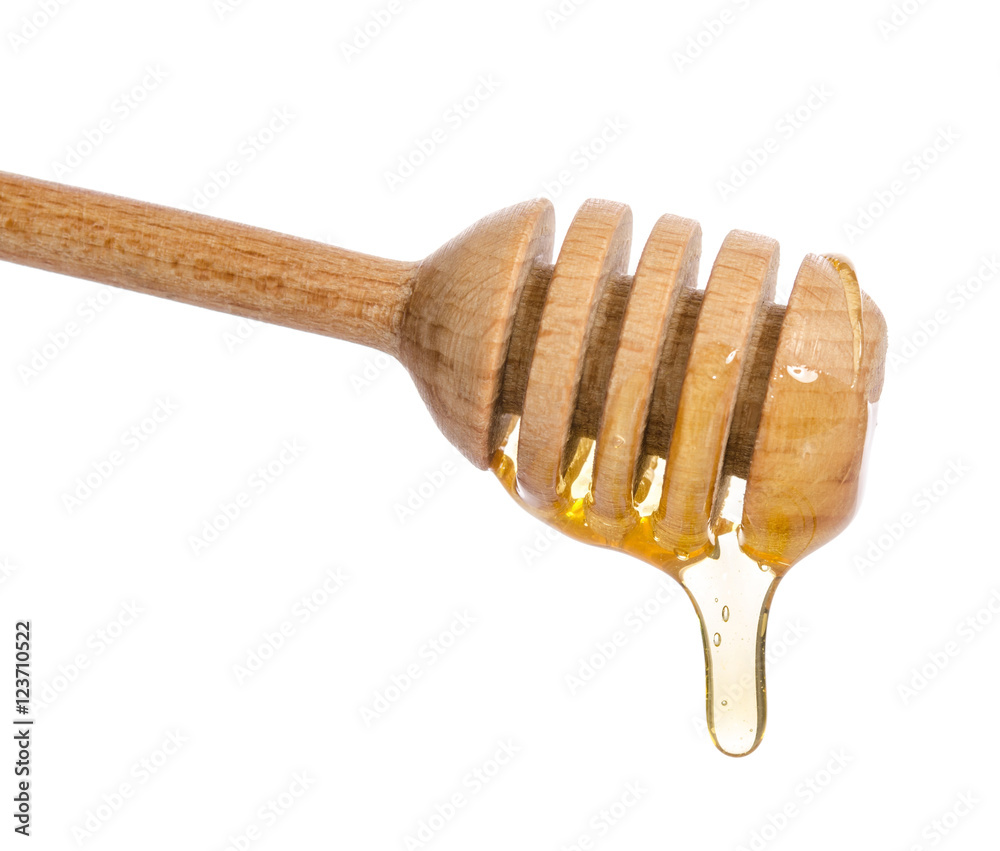 Honey dripping from a wooden honey dipper isolated on white back