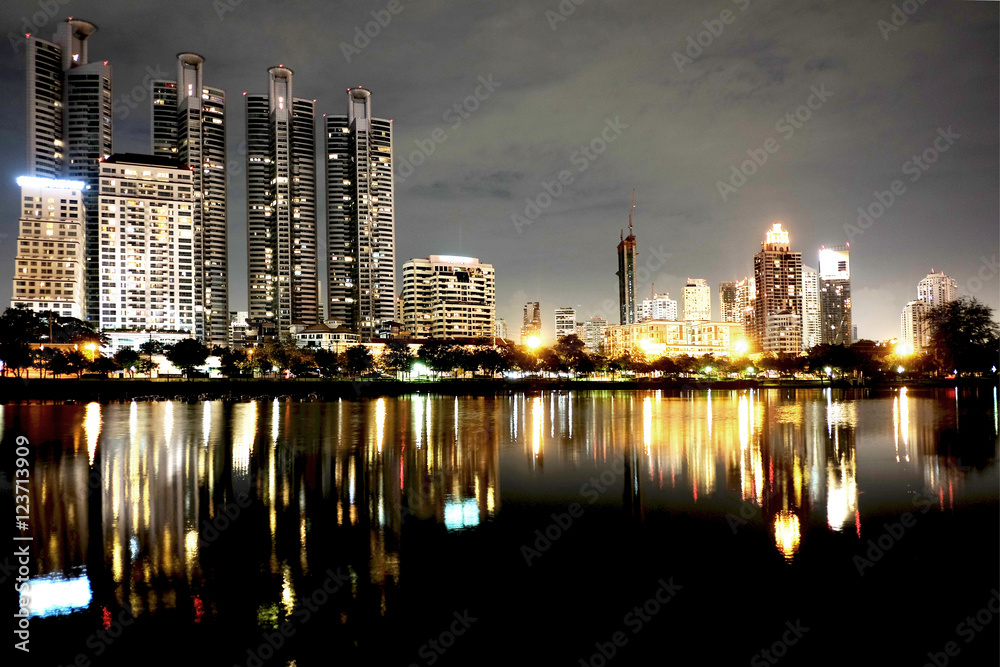 Obraz premium HIGH RISE BUILDING AT NIGHT Cityscape of group of buildings standing behind a big lake at night.