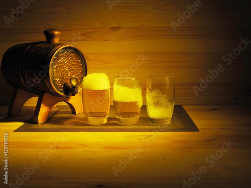 Barrel and glass of light beer on a wooden background