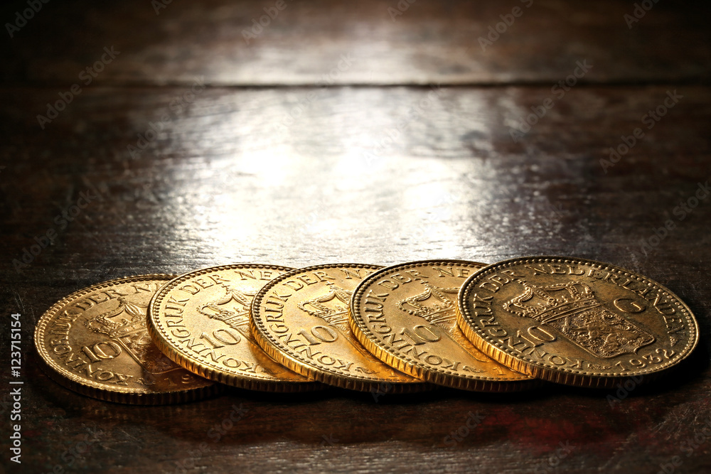 Dutch Wilhelmina gold coins on rustic wooden background Dutch Wilhelmina gold coins on rustic wooden background