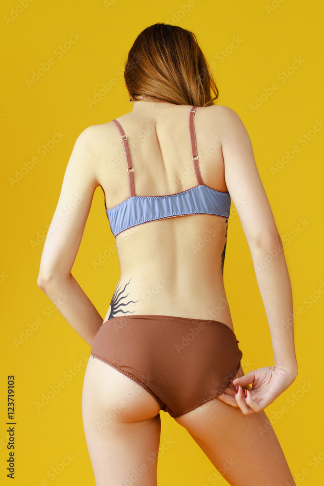 Skinny girl on a yellow background in beautiful lingerie Stock Photo |  Adobe Stock
