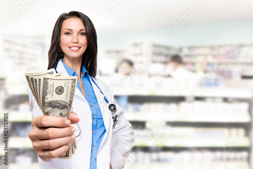 Tableau sur toile Female Doctor pharmacist with handful o dollars in pharmacy