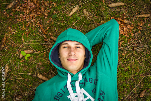 Ein lächelnder Mann im Wald auf dem Rücken liegend 