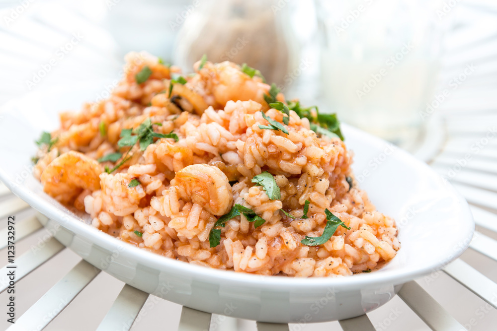 Tasty risotto with Shrimp, fresh herbs vegetables on a white pla Tasty risotto with Shrimp, fresh herbs vegetables on a white pla