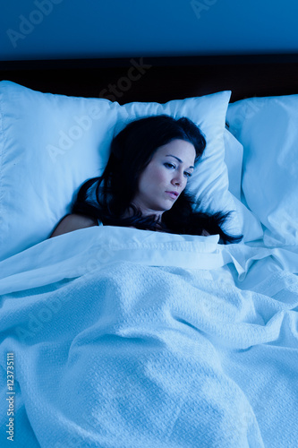 Sick insomnia suffering woman in bed near midnight photo