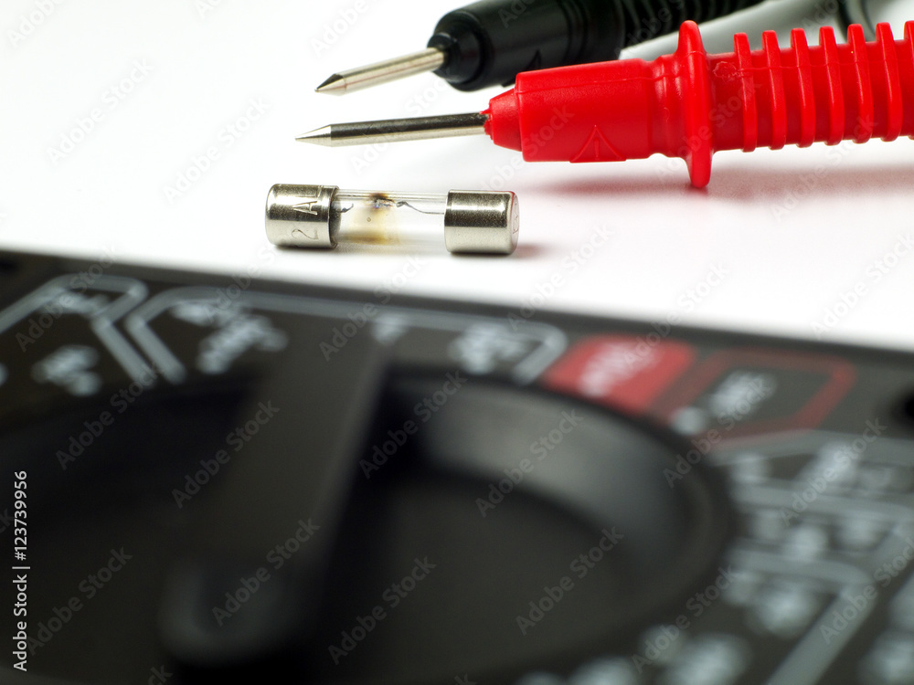 blown fuse macro with multimeter probes in background and multimeter in