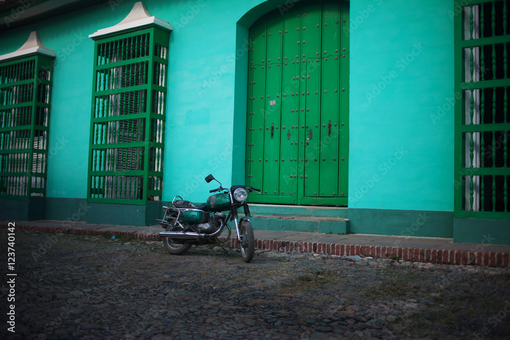 Green motorcycle on the street, on background of green houses, color effect Green motorcycle on the street, on background of green houses, color effect
