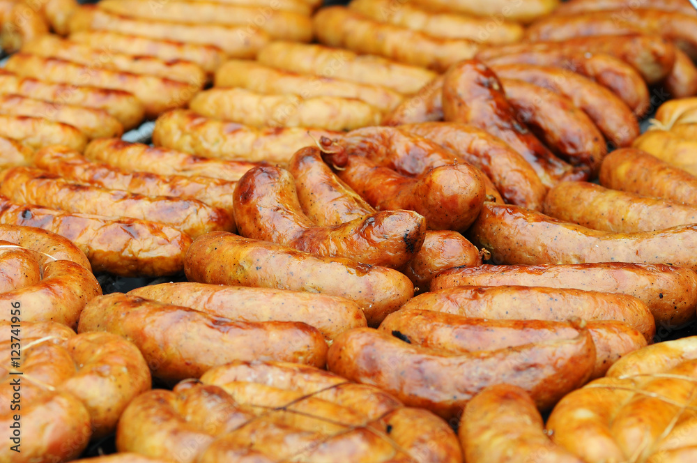 Fresh sausage and hot dogs grilling outdoors on a gas barbecue grill. Closeup of sausage on the grill Fresh sausage and hot dogs grilling outdoors on a gas barbecue grill. Closeup of sausage on the grill