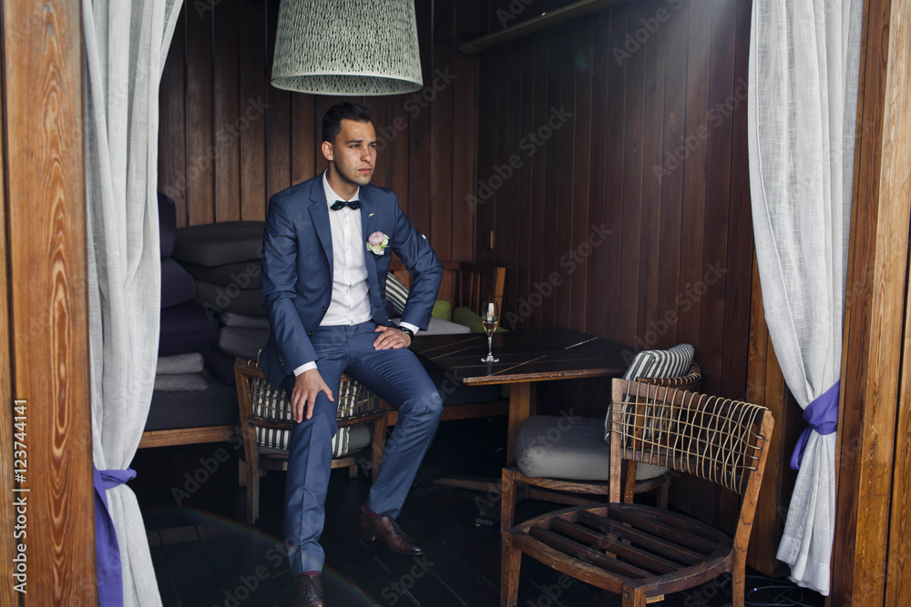 charming groom sits on the chair outdoors charming groom sits on the chair outdoors