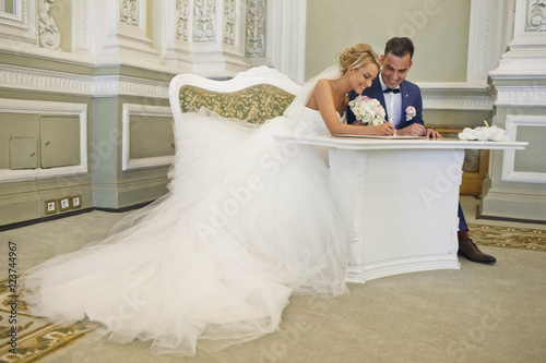 фотографія young married couple sign the marriage certificate