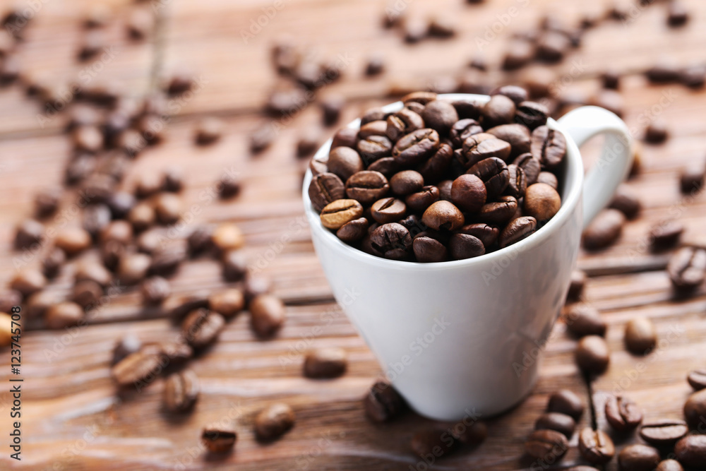 Fototapeta premium Roasted coffee beans in cup on a brown wooden table