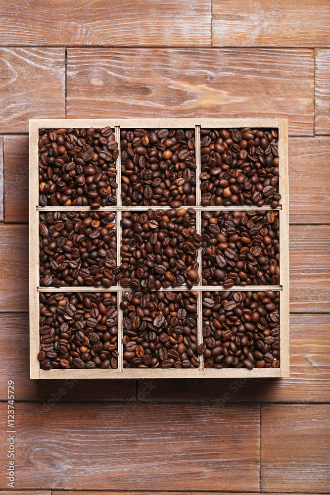 Roasted coffee beans in wooden basket on brown table Roasted coffee beans in wooden basket on brown table