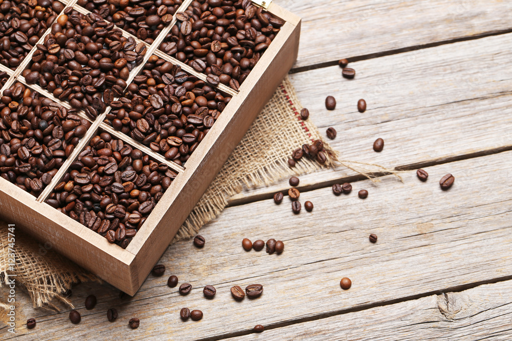 Roasted coffee beans in wooden basket on grey table Roasted coffee beans in wooden basket on grey table