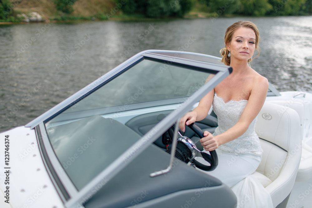 Gorgeous bride is trying to drive  a boat