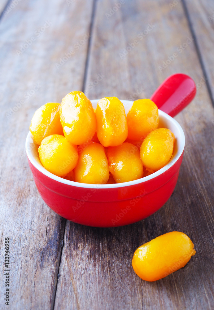 Close up of traditional Thai sweet jack fruit seeds dessert in a red bowl on a wooden table. Close up of traditional Thai sweet jack fruit seeds dessert in a red bowl on a wooden table.