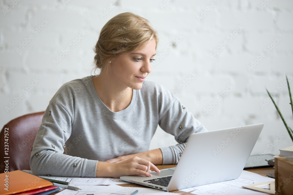 Portrait of a young attractive student girl sitting at the desk working with a laptop, education concept photo, lifestyle Portrait of a young attractive student girl sitting at the desk working with a laptop, education concept photo, lifestyle