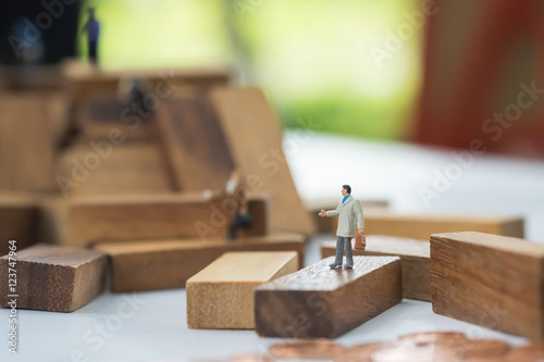 Miniature businessman on wooden block or obstacles among competi
