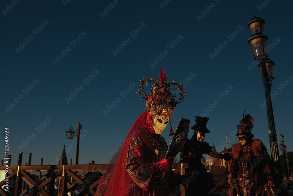 Queen in red carnival costume walks under a deep blue sky along Queen in red carnival costume walks under a deep blue sky along