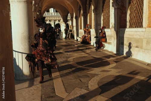 People in carnival dresses walk around the Venice in the morning photo