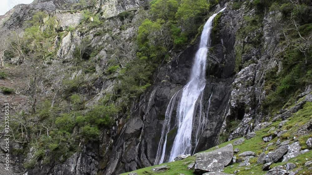 Wide shot of a Waterfall, white water flowing down over moss covered rocks , Aber falls, Wales UK Wide shot of a Waterfall, white water flowing down over moss covered rocks , Aber falls, Wales UK