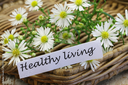 Healthy living card with chamomile flowers on wicker tray
