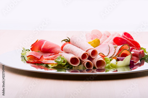 Food tray with delicious salami, pieces of sliced ham, sausage, tomatoes, salad and vegetable - Meat platter with selection