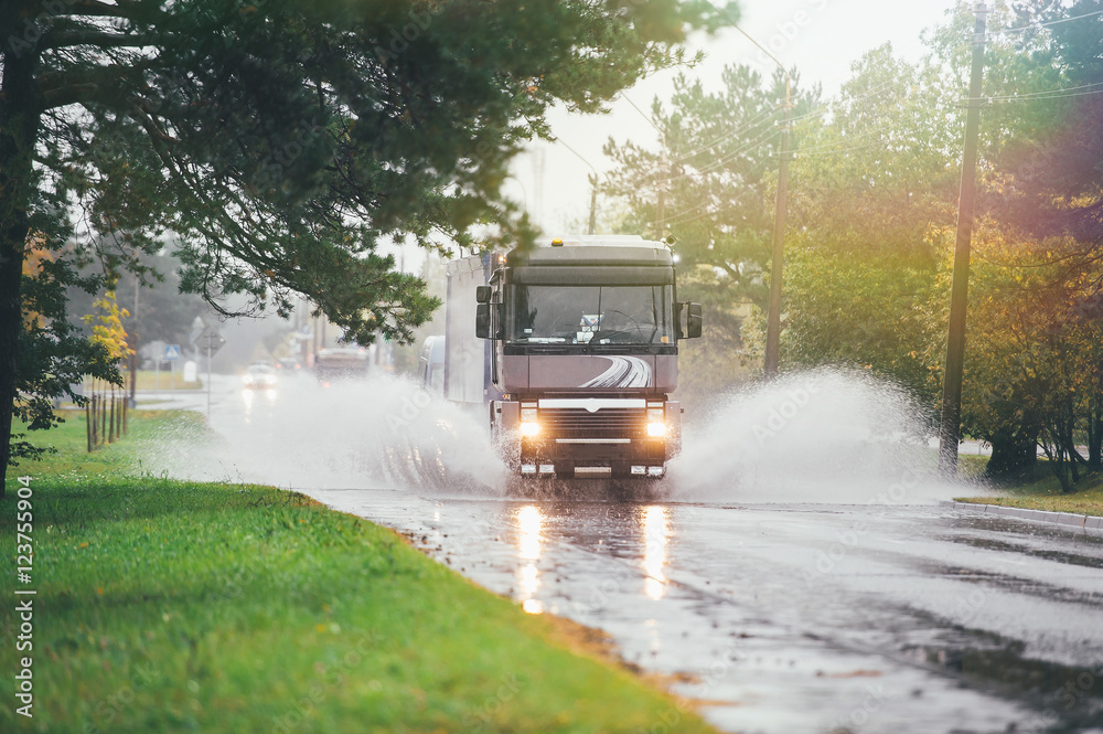 Lorry on wet road rides through a puddle