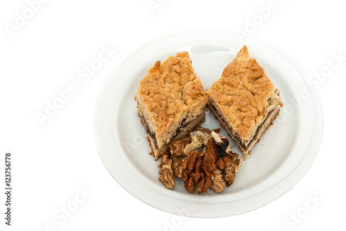 Fruitcake with jam and kernels of walnuts on a white plate