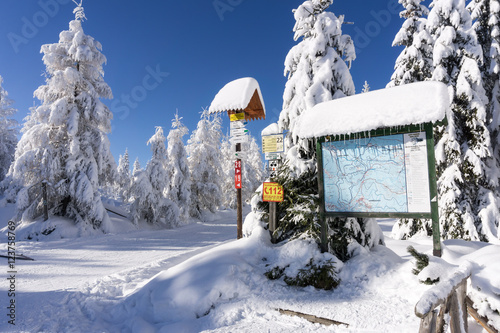 Mountain trail sign with directions and hiking or skiing time in winter. Jizera Mountains, Jakuszyce, Poland, Europe.