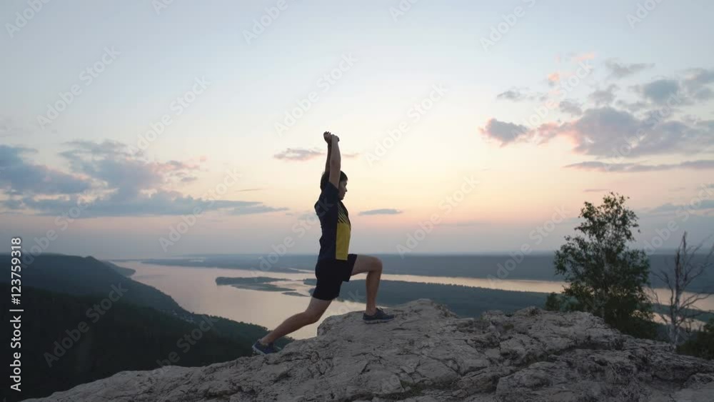 young man doing exercise to stretch the top of the mountain young man doing exercise to stretch the top of the mountain