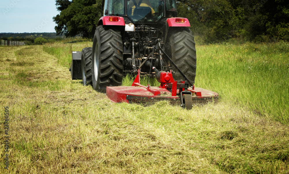 Fototapeta premium Farming: Large red tractor moving green farmers pasture, motion close up 