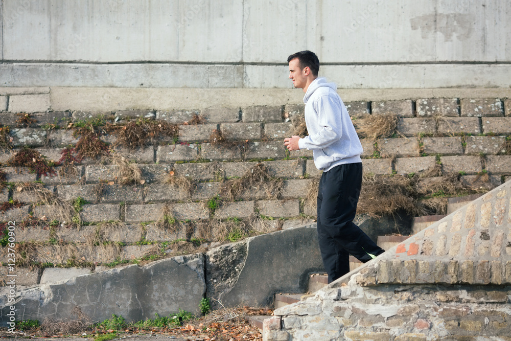 Side view of an attractive young man jogging on the street. He is running down the stairs. Side view of an attractive young man jogging on the street. He is running down the stairs.