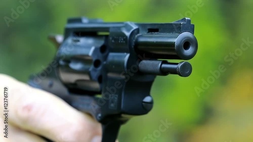 Man shoots a revolver, video with sound. Man cocks and shoots. Soldier shoots a pistol. Man with black gun, raise the cock, cock the gun, close up photo