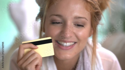 A young woman uses a golden credit card online lying on the couch. photo