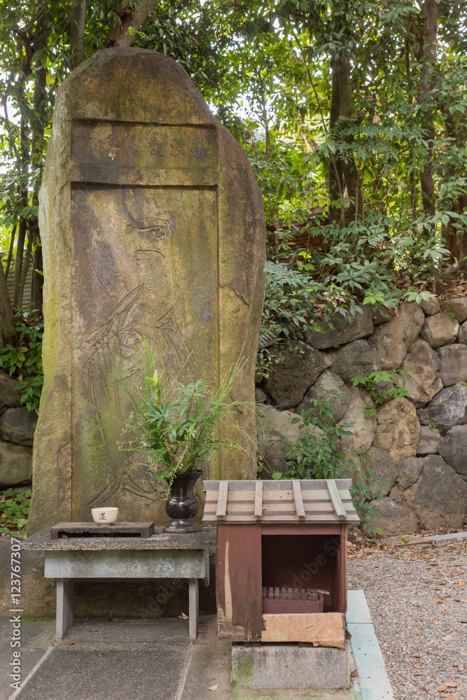 Naklejka premium Kyoto, Japan - September 16, 2016: A stela with the chiseled picture of Quan Yin stands in a corner of the formal garden at Shorenin Buddhist Temple. Weather took its toll on the old stone. 