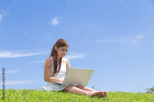 青空の下でパソコンを操作する若い女性