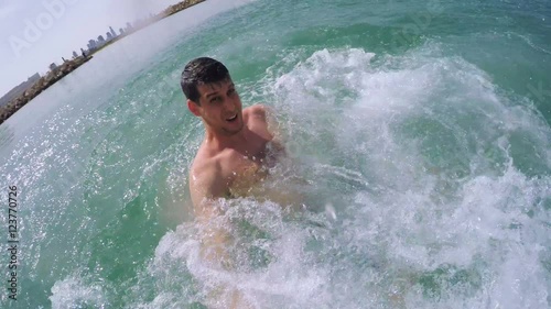 Young man filming himself thrown into the water from a boat by his friends.