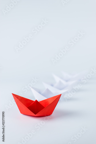 red paper ship leading among white