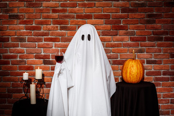 Ghost holding wine over brick background. Halloween party.
