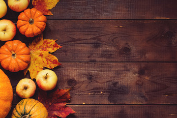 Thanksgiving background: Apples, pumpkins and fallen leaves on wooden background. Copy space for text. Halloween, Thanksgiving day or seasonal background. Design mock up.