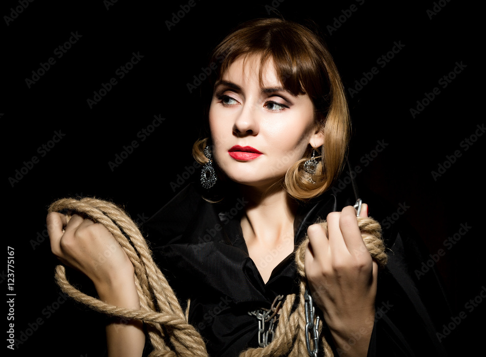 mysterious young woman holding rope. on a dark background Stock-Foto
