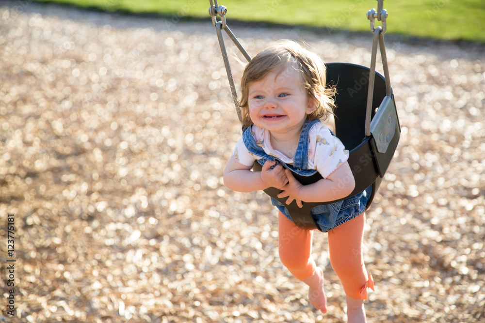Cute baby girl having fun on a swing